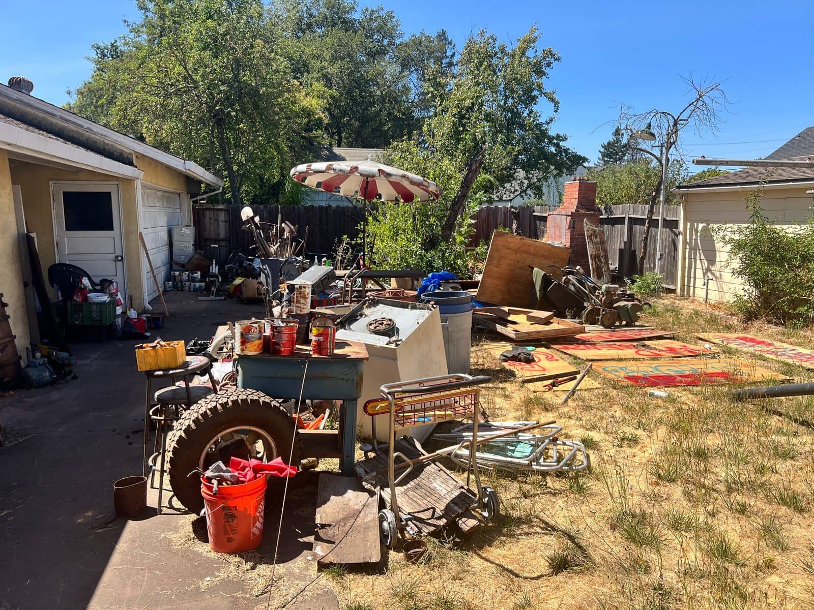 A backyard full of stored items and overgrown landscaping at a home we bought as-is.
